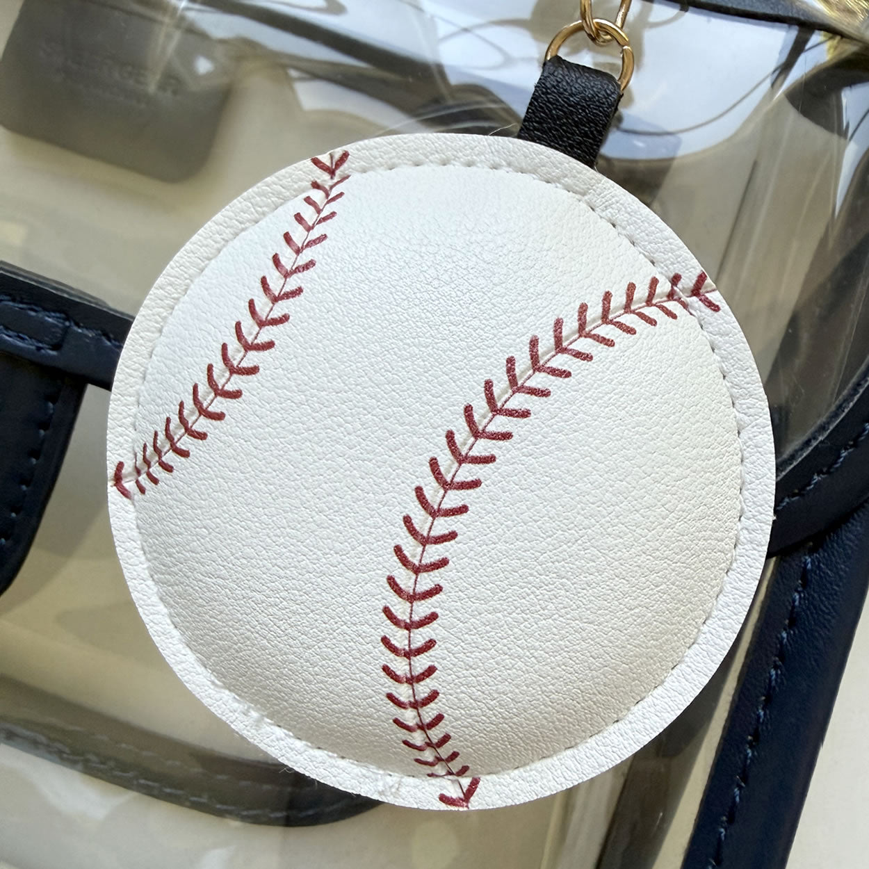 Baseball-shaped keychain handbag accessory with red stitching on a faux-leather surface