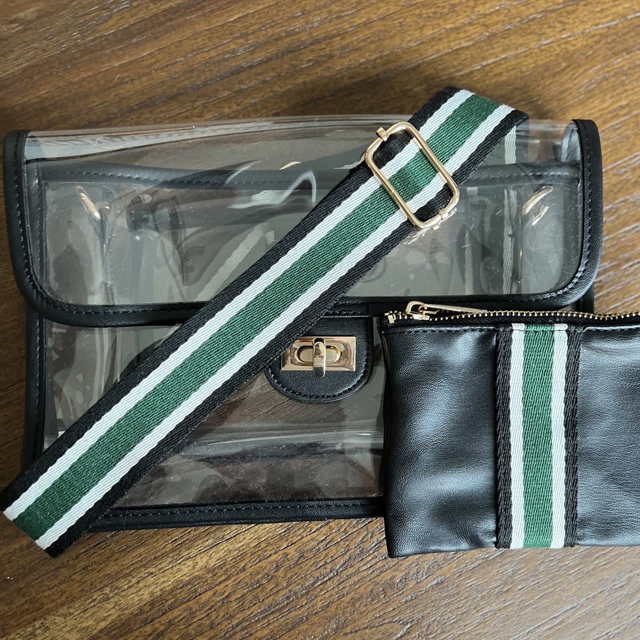 Clear, stadium approved purse with black trim and striped black and green strap