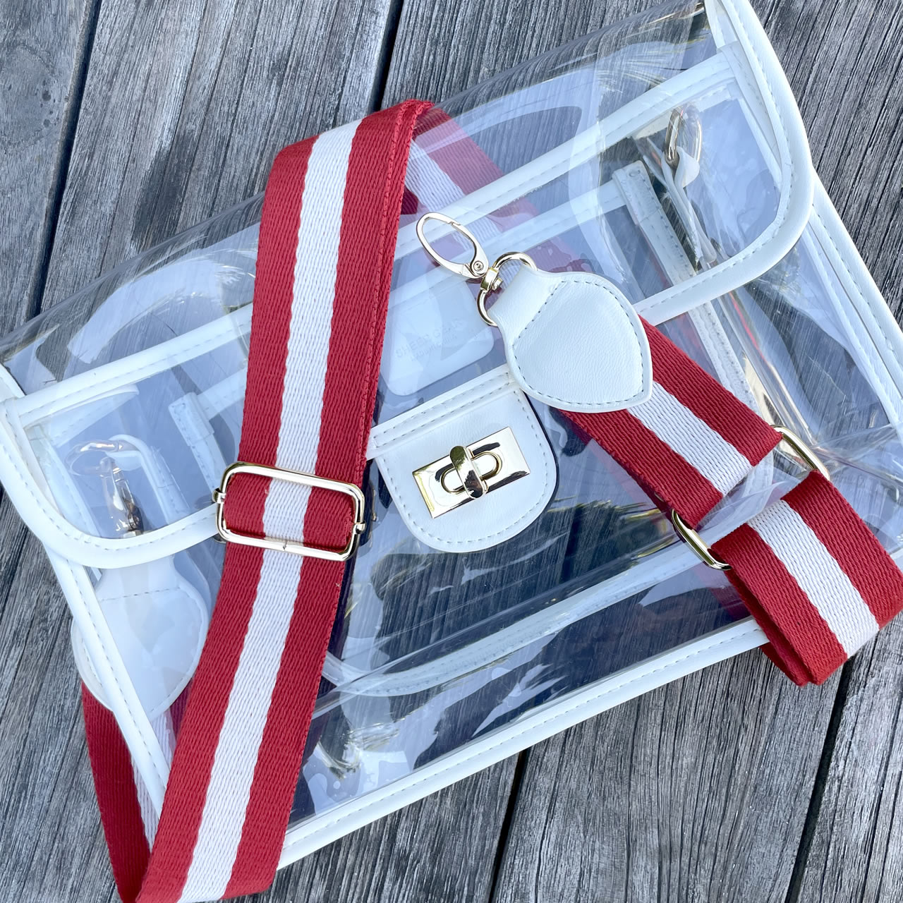 Clear, stadium approved purse with striped read and white strap
