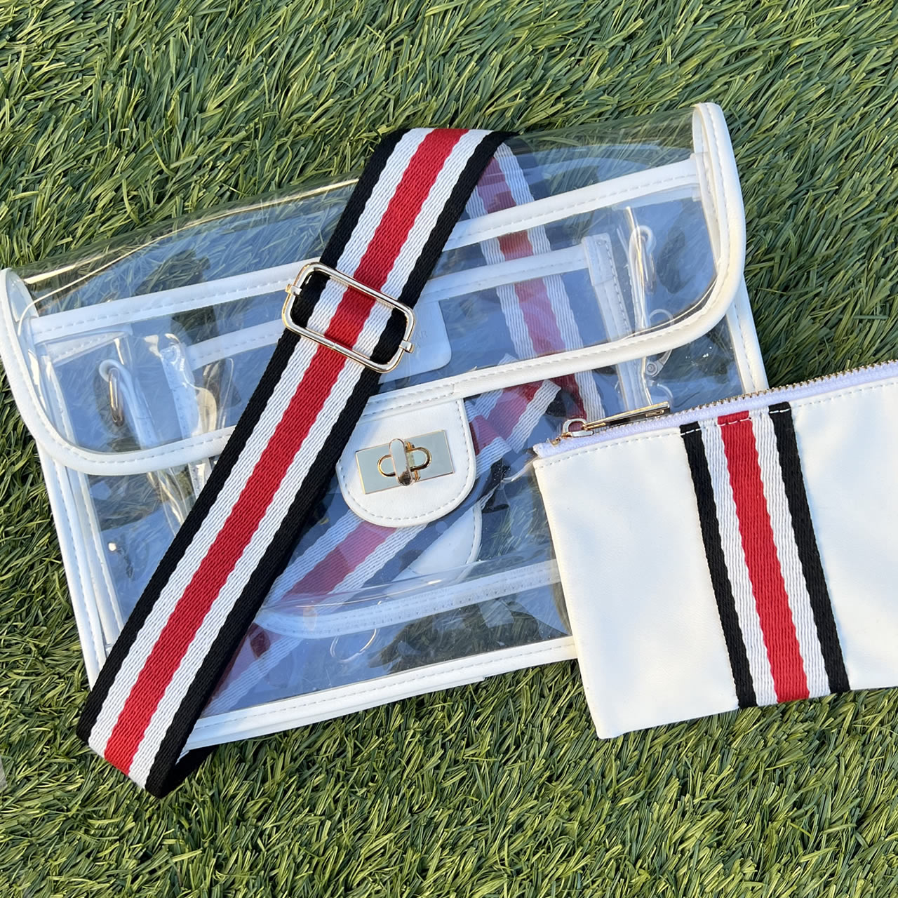 Clear, stadium approved purse with white trim and striped black, red, and white strap
