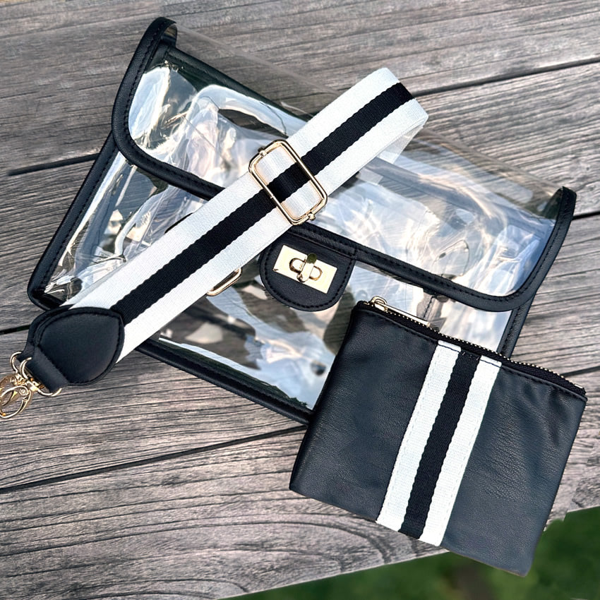 Clear stadium handbag with black and white strap and matching pouch on a wooden surface