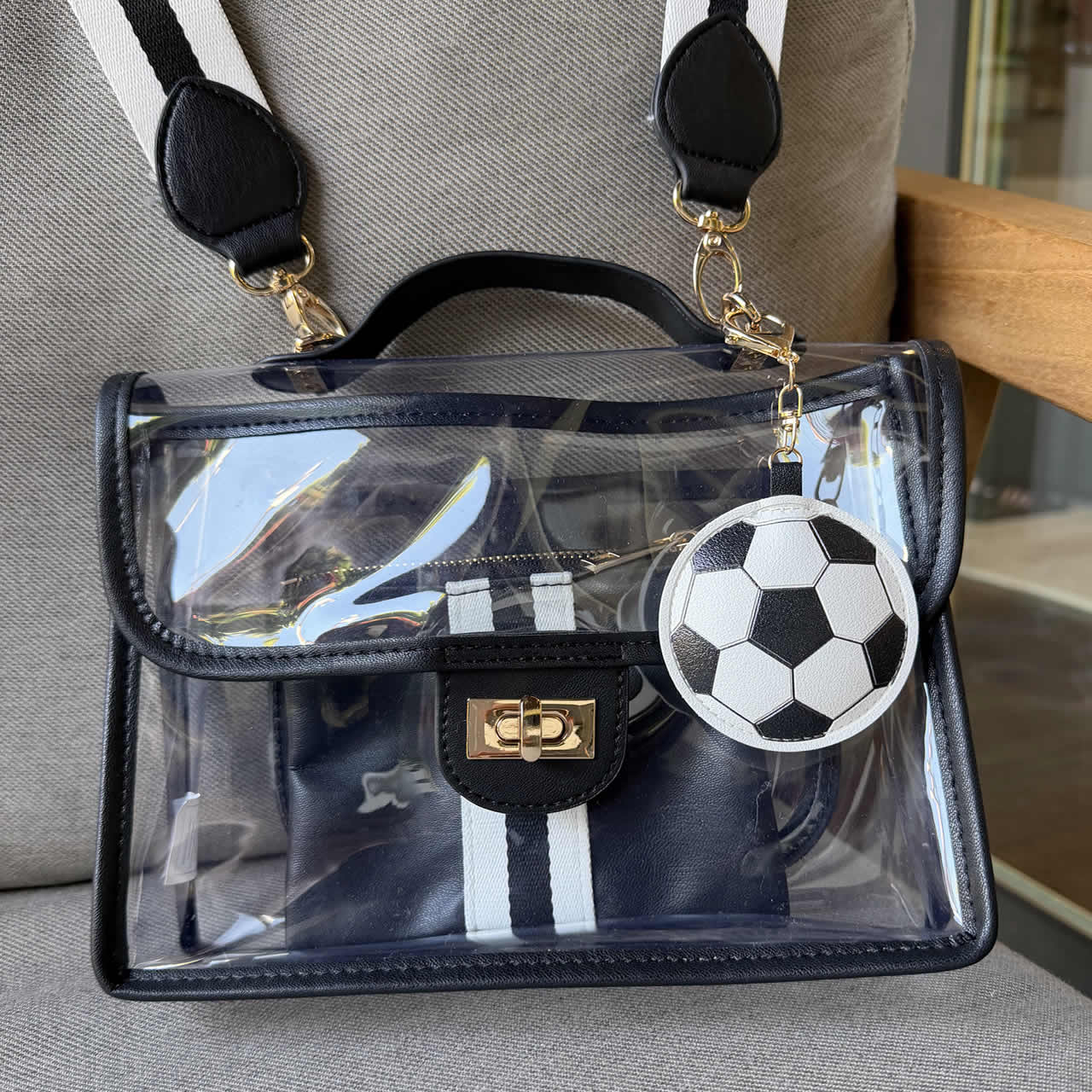 Large soccer ball charm purse accessory hanging on a black and white stadium approved handbag.