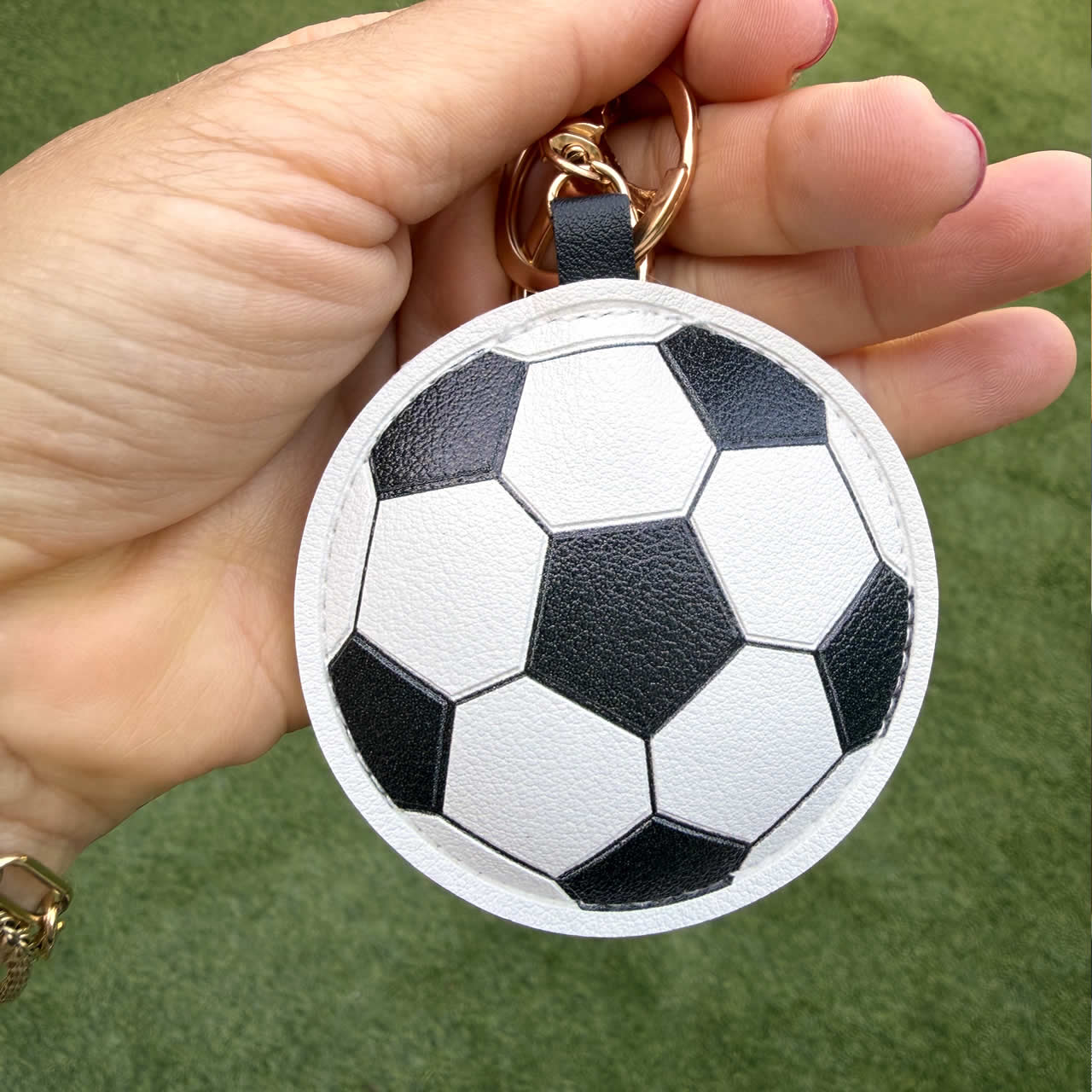 Soccer ball, clip-on purse accessory being held to show size.