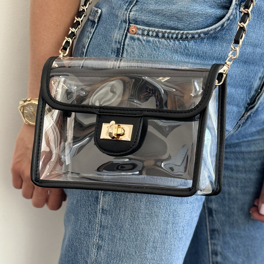 Clear fanny pack that converts into a game-day handbag being worn as a crossbody bag by a person wearing blue jeans.
