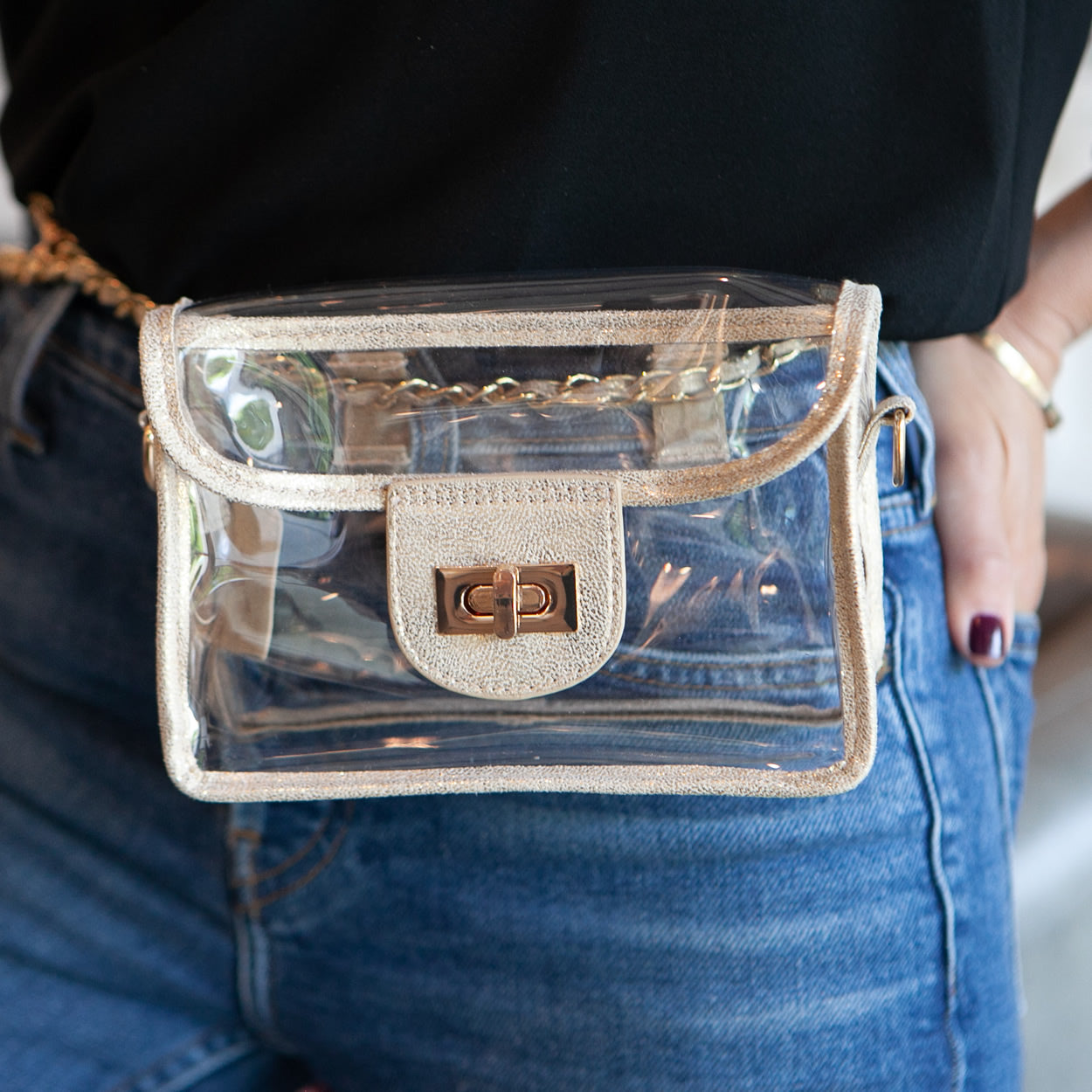 Clear, stadium approved gold faux-leather trim purse with a gold chain being worn as a convertible fanny pack