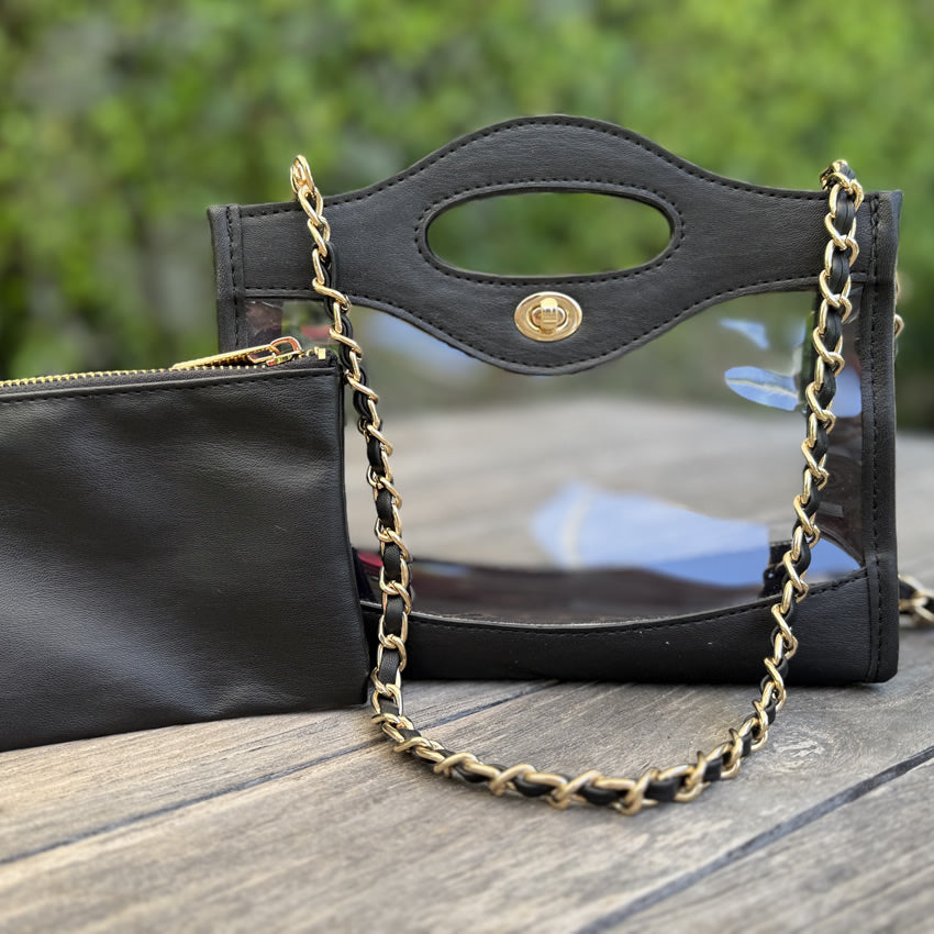 Black handbag with gold chain strap on a wooden surface