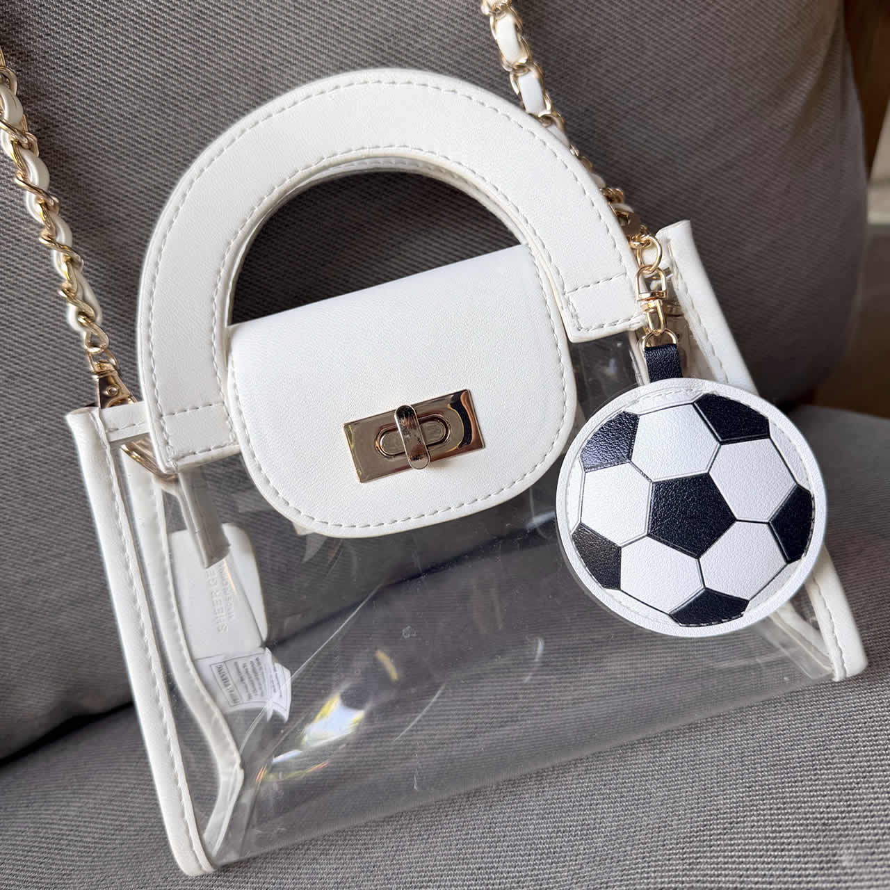 Soccer ball purse charm handing on a white stadium-approved handbag
